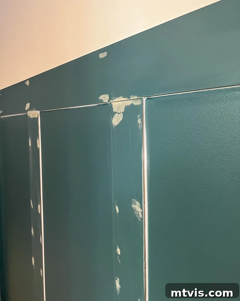 Effortless Board and Batten Accent Wall DIY 10 Applying caulk to the seams of a newly installed board and batten wall