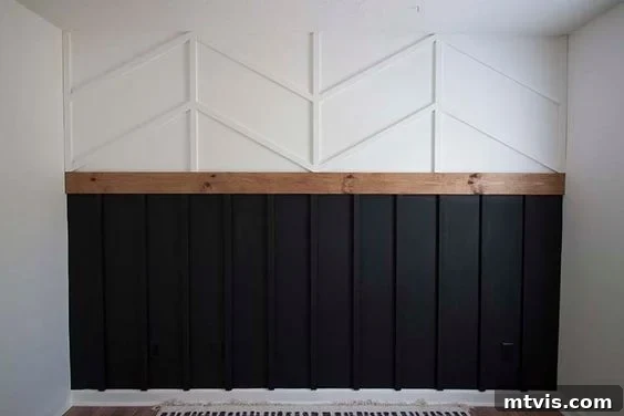 A board and batten wall is designed with traditional vertical boards on the bottom, painted dark grey and a white herringbone pattern on top. 