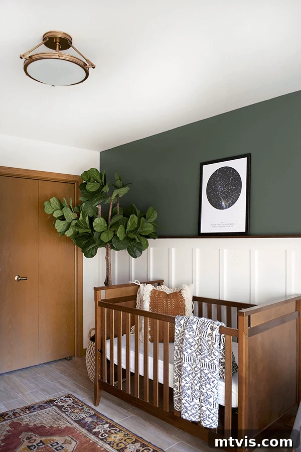A nursery features a dark wood crib against a white board and batten wall. The olive-green wall above the crib includes a poster of the night sky.