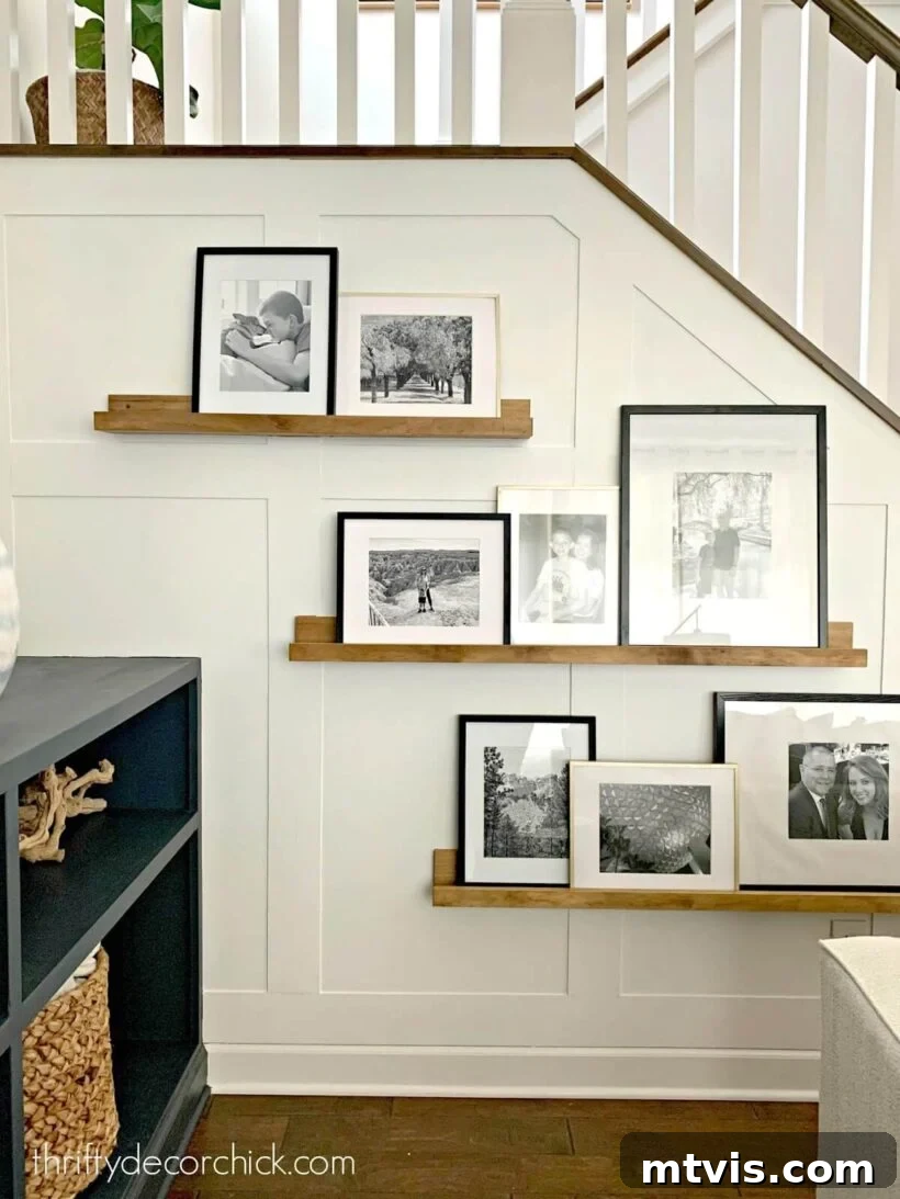 A board and batten wall includes photo ledges for a portrait gallery by a staircase. 