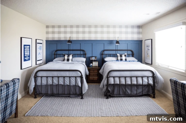Two twin beds decorated in blue are shown against a dark blue board and batten accent wall with buffalo plaid at the top. 