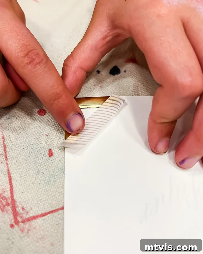 Close-up shot of hands carefully taping gold photo corners onto the edges of a black and white photograph.