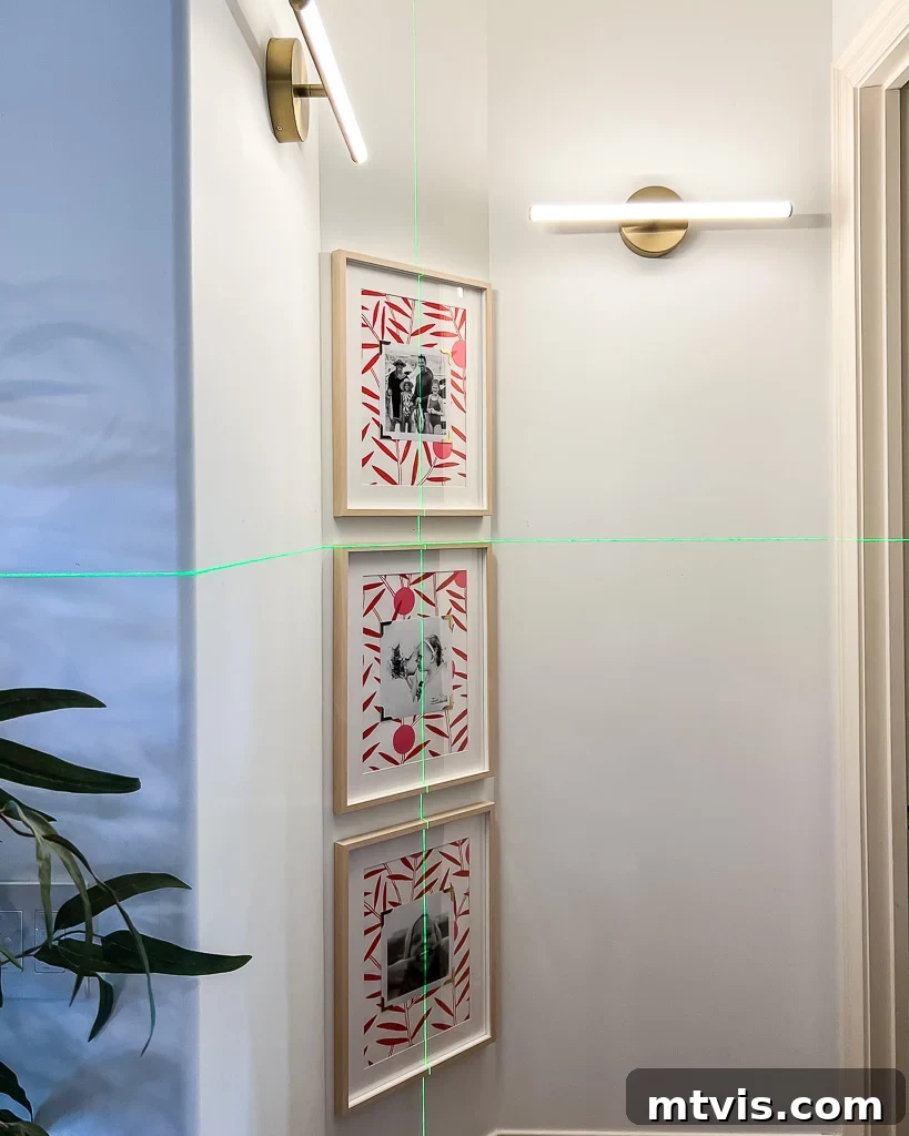 A completed family photo gallery wall with framed photos and wallpaper backgrounds, perfectly hung in an alcove, showcasing a unique home decor idea.