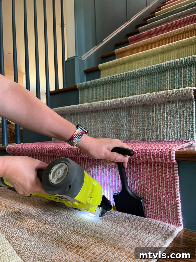 Ultimate Guide to Stair Runner Installation 13 Woman using a bolster chisel to tuck and staple a DIY stair runner at the base of a stair riser.