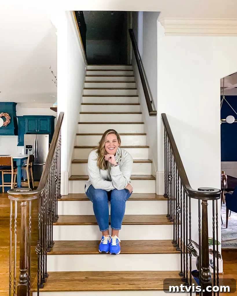 Ultimate Guide to Stair Runner Installation 3 Tasha Agruso of Kaleidoscope Living sitting on a basic staircase before makeover, highlighting its original condition.