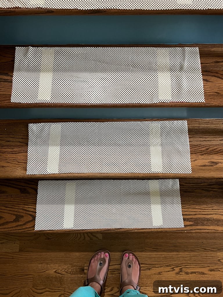 Ultimate Guide to Stair Runner Installation 8 Stair runner with honeycomb rug pad taped onto the stair tread, centered and ready for runner installation.