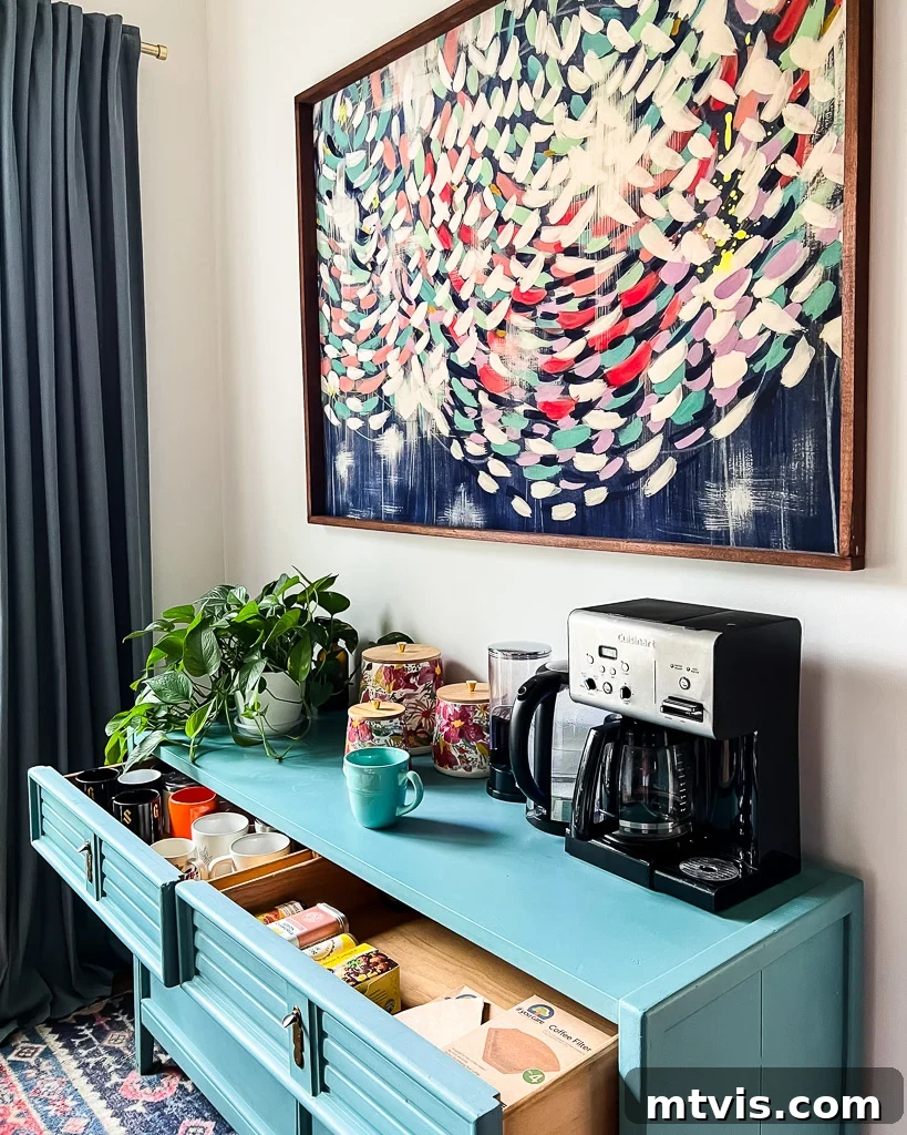 Everyday Kitchen Cabinet Organization 11 A light-blue dresser acts as a coffee nook in the corner of the room. A blue-themed abstract art piece hangs over the nook, which has a coffee pot, jars for sugar, a plant and more.