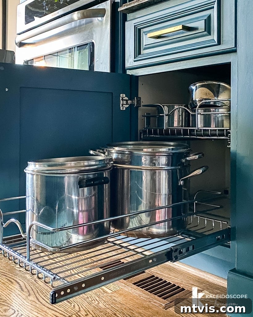 Everyday Kitchen Cabinet Organization 5 Rev-a-Shelf pots and pans organizers with deep pots pulled out from the bottom shelf of a blue cabinet.