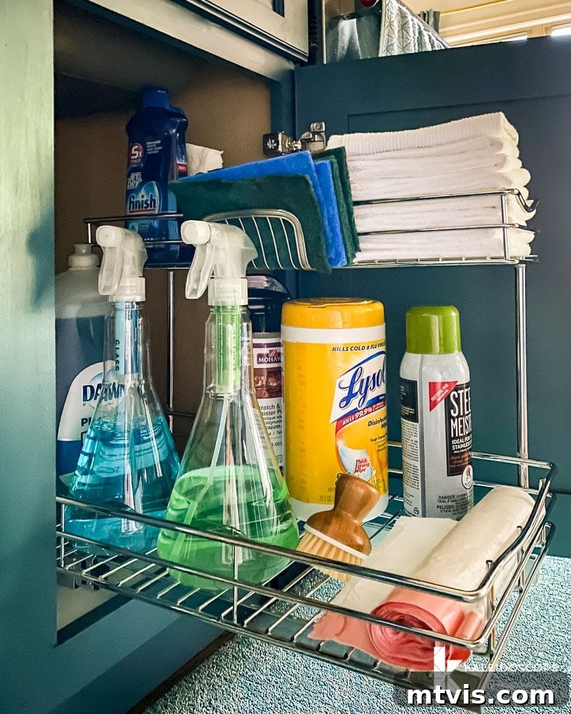 Everyday Kitchen Cabinet Organization 6 An under-the-sink organizer on a pull-out shelf in a lower kitchen cabinet has sponges, spray cleaners, towels, and garbage bags.