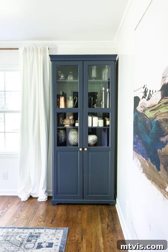 Upgraded navy IKEA cabinet in a dining room, painted with Benjamin Moore Hale Navy, complementing the room's art and rug.