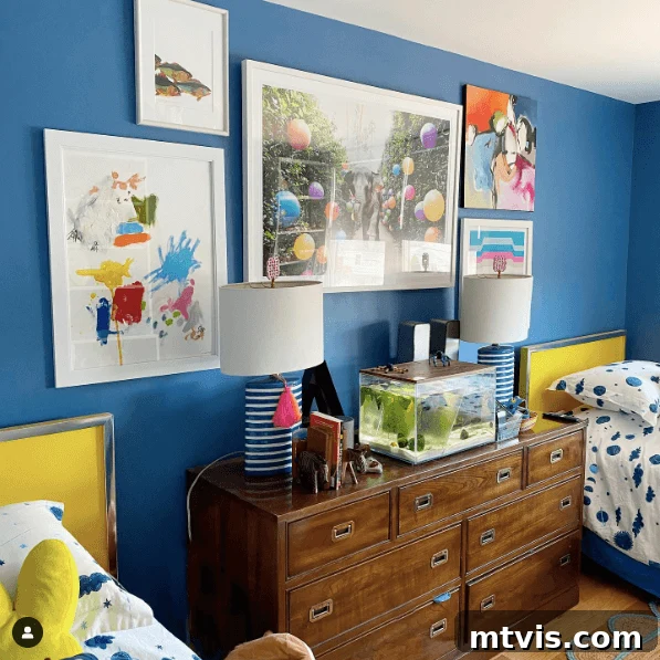 Vibrant blue walls in a shared boys' bedroom, painted with Farrow & Ball Ultra Marine Blue, adorned with colorful art.