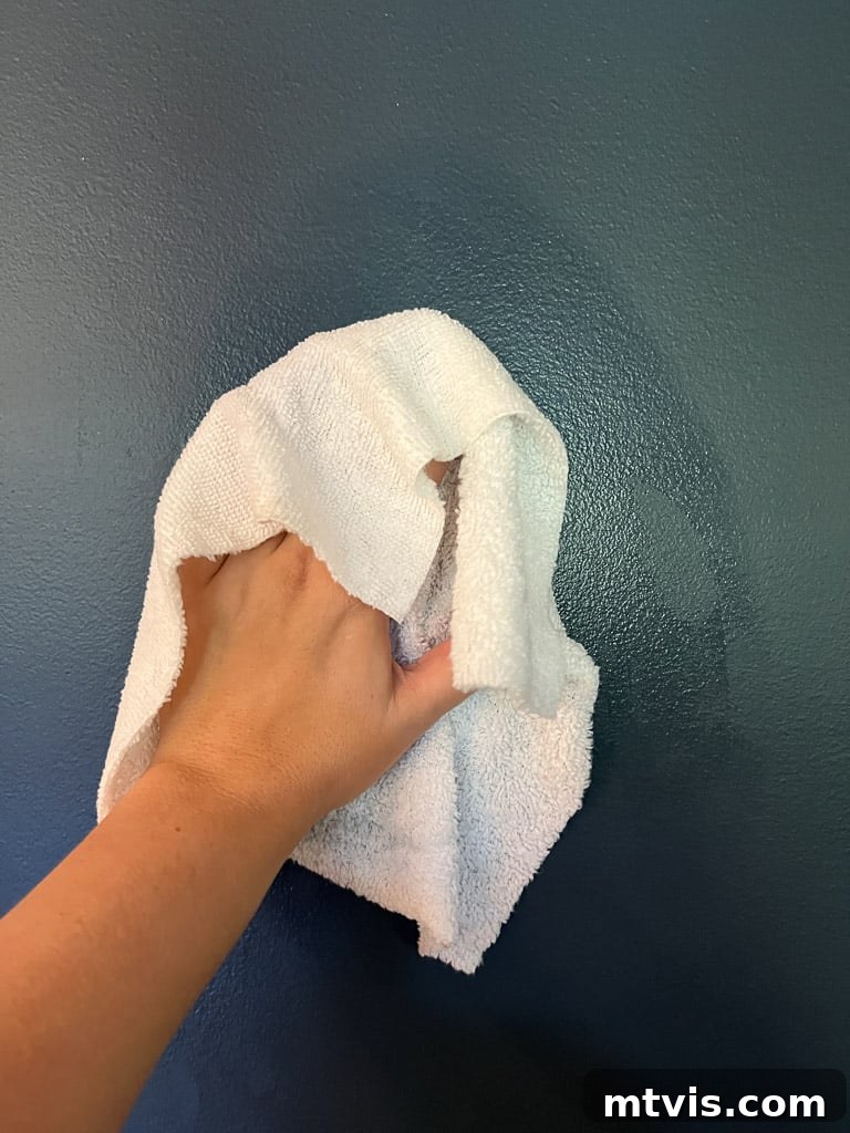 Cleaning wall surface with a damp rag for wallpaper preparation