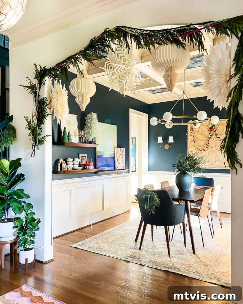 Realistic Norfolk pine artificial garland beautifully framing the cased-opening of a dining room decorated for Christmas.