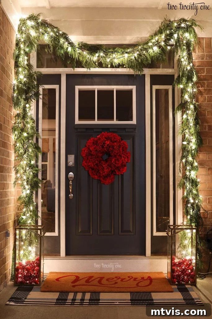Festive Front Porch Christmas Magic 8 Front porch Christmas decorations can be simple and elegant like this beautiful front porch garland with white lights and a red flower door wreath, seen at night to create a welcome glow. Design by Two-Twenty-One.