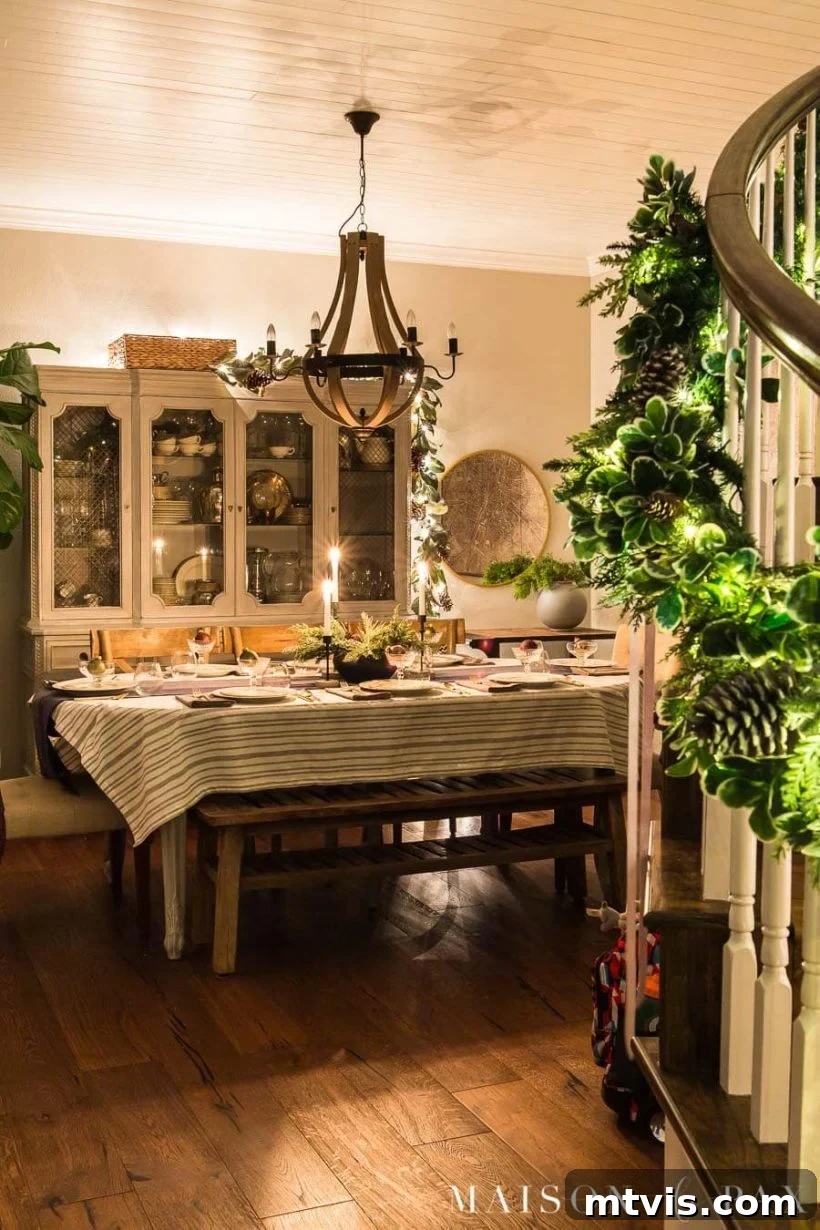 Simple yet glowing dining room Christmas decorations, highlighted by garland and string lights on a china hutch.