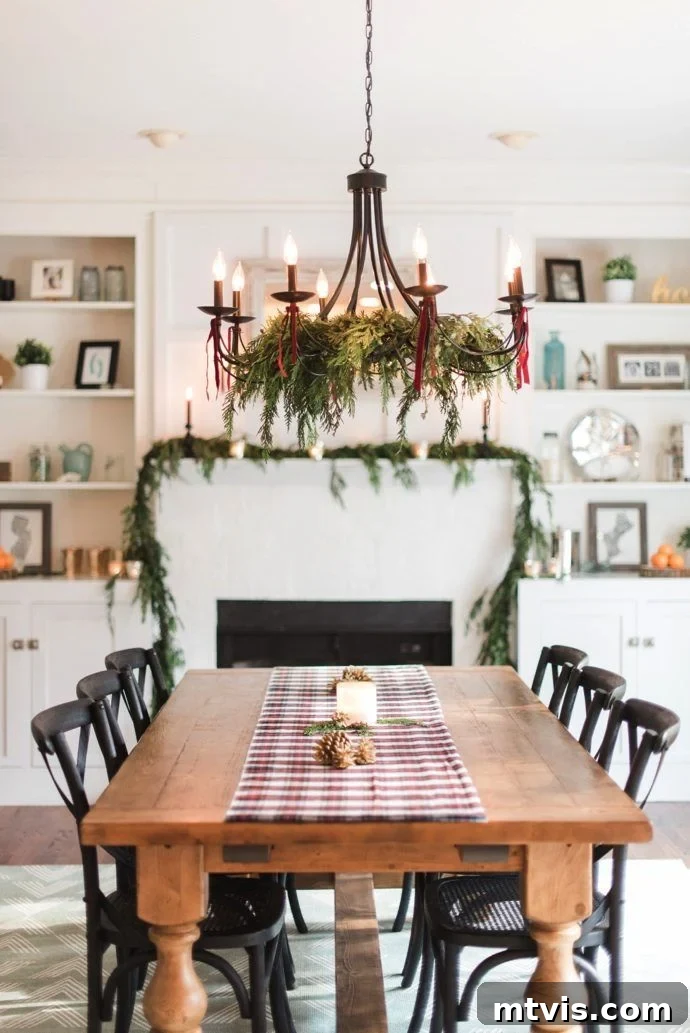 Dining room chandelier elegantly decorated for Christmas with lush greenery and festive ribbons.