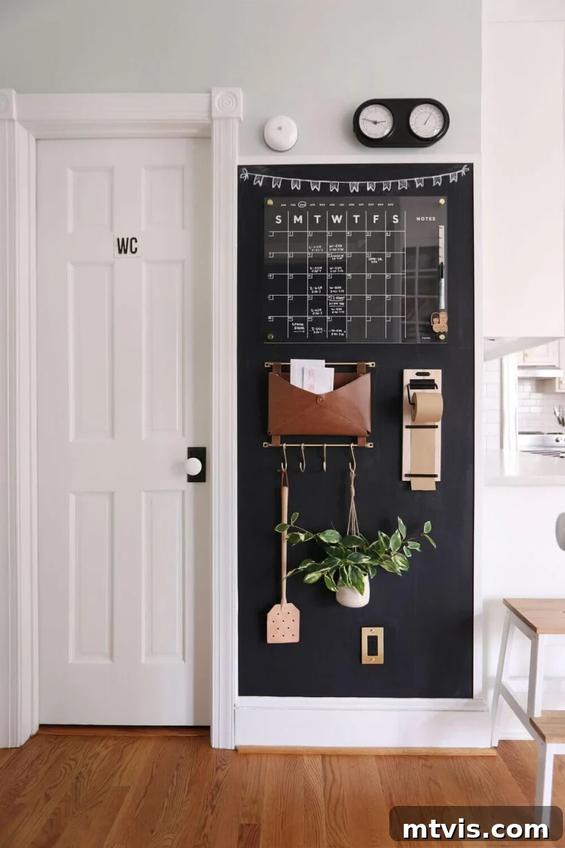 Conquer Family Chaos: Calendar Strategies for a Peaceful Home 11 A modern chalkboard wall serving as a chic command center, featuring an elegant acrylic calendar, a leather pocket, and hooks for keys, blending style with comprehensive family organization.