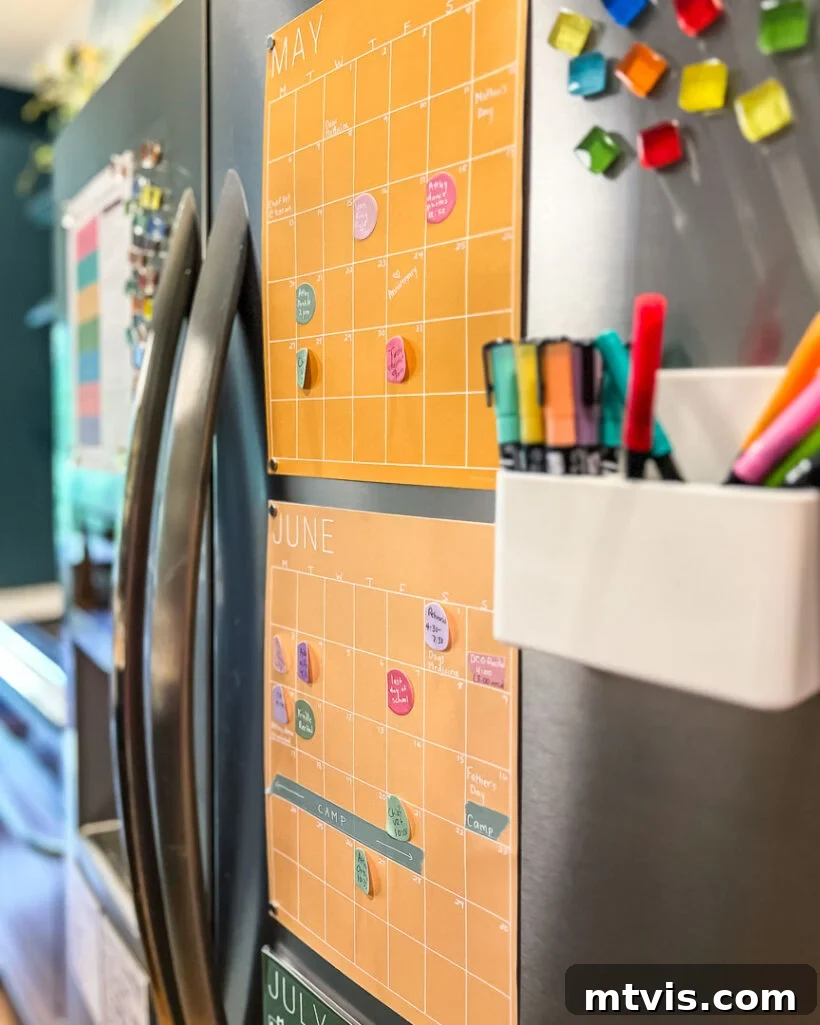 Conquer Family Chaos: Calendar Strategies for a Peaceful Home 3 A colorful monthly family calendar from Kaleidoscope Living, featuring a rainbow palette, displayed prominently on a kitchen refrigerator for easy access and visual organization.