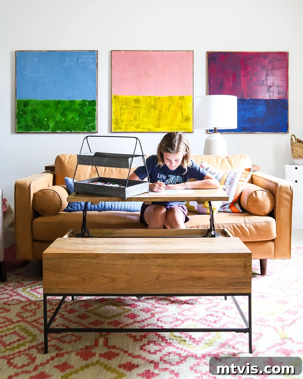 Playful and Chic Playroom Design Guide 11 A young girl sits on a couch while using the raised desk portion of a coffee table. Unique coffee tables that are multi-functional are great playroom ideas.