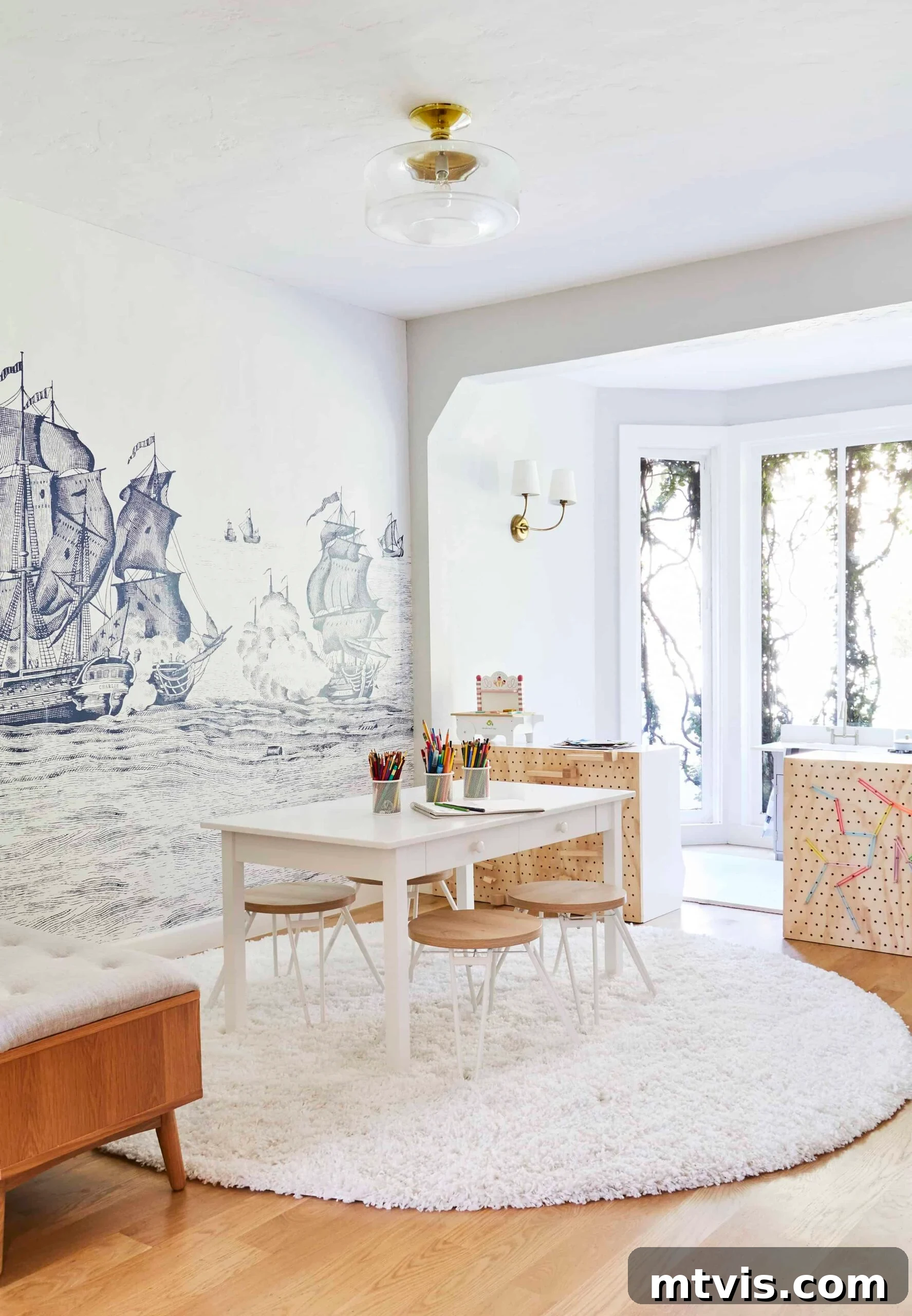 Playful and Chic Playroom Design Guide 16 This playroom idea has a blue mural of old ships on a wall behind a white desk with four stools and large windows.