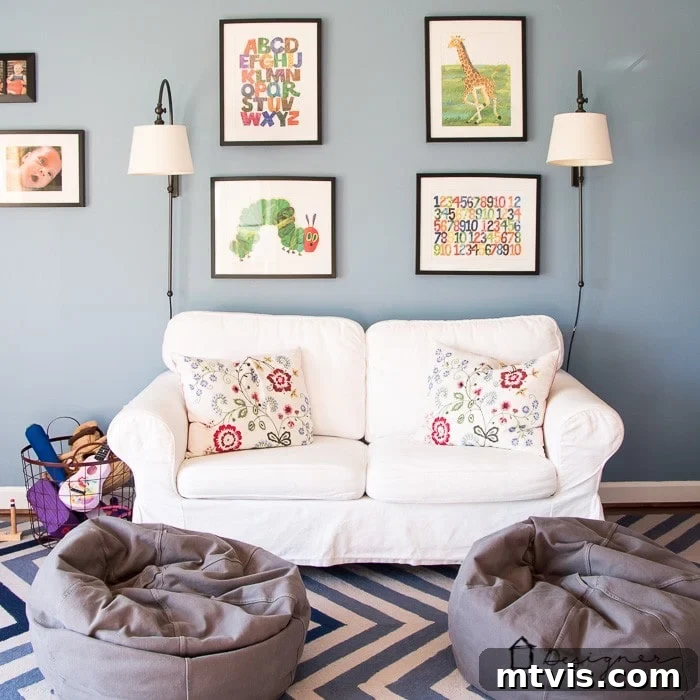 Playful and Chic Playroom Design Guide 18 A playroom with blue-grey walls, a white loveseat and two child-sized bean bags. Framed children's book covers are on the wall. Good playroom ideas include comfortable seating.