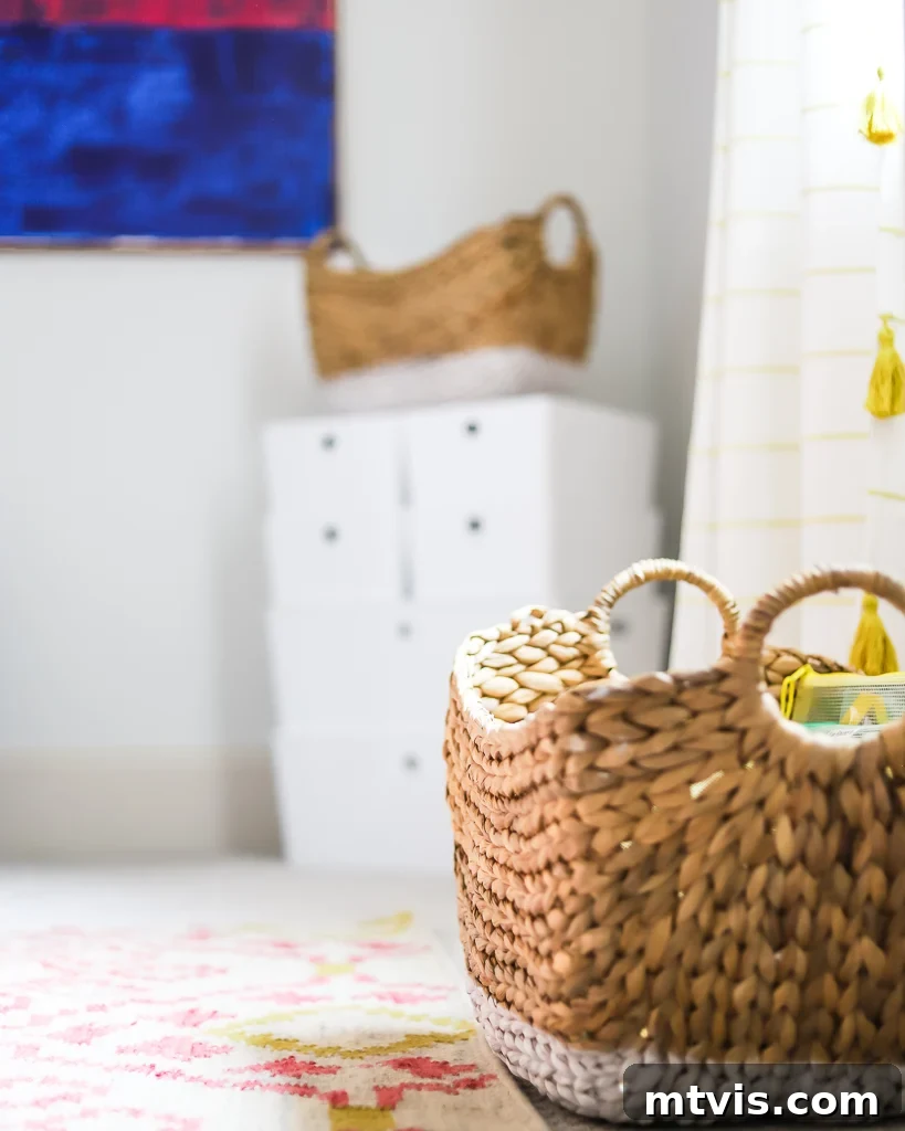 Playful and Chic Playroom Design Guide 7 A closeup of the corner of a weaved basket on a light, colorful rug. Blurry storage bins and a bright blue square painting are in the background.