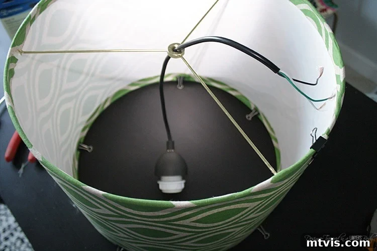 Threading the pendant light kit wire through the top finial ring of the drum shade