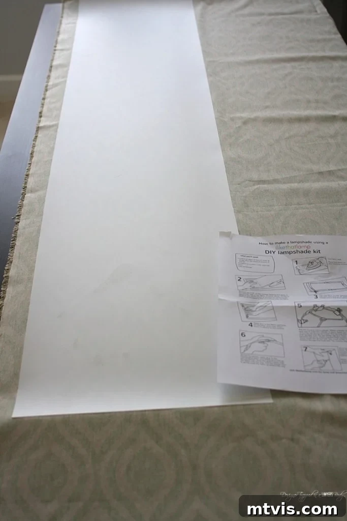 Carefully pressing styrene onto fabric, leaving fabric overhang for drum shade assembly