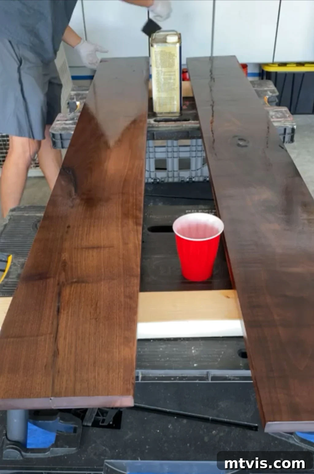 Applying Danish Oil to a DIY wall shelf with a cloth, enhancing the wood's natural grain and color.
