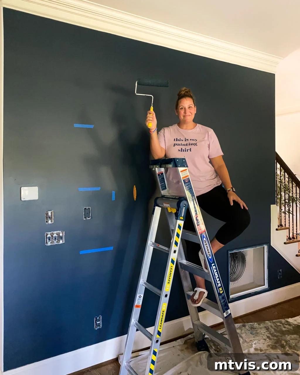 Using painter's tape to mark stud locations and the desired height for DIY wall shelves on a blue wall.