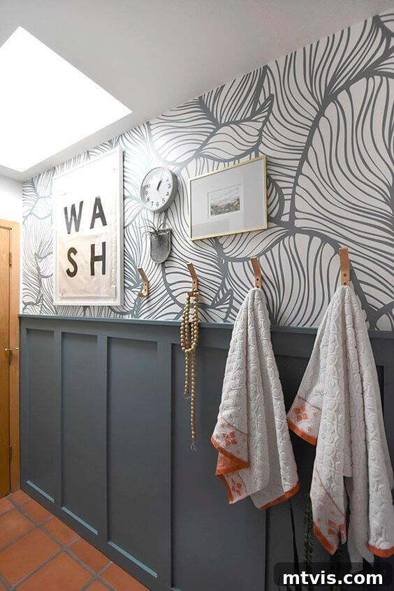 Sophisticated Serenity: Top Blue-Gray Paint Colors 12 A bathroom wall with blue gray paint colors on wainscotting board and printed wallpaper. A sign says "wash" and towels hang on hooks.
