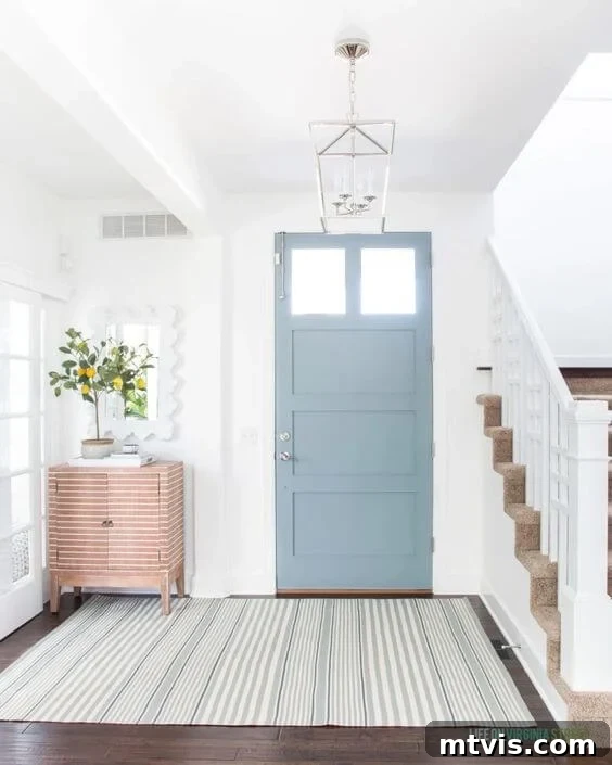 Sophisticated Serenity: Top Blue-Gray Paint Colors 3 A light blue-gray front door next to a staircase and a side table showcases