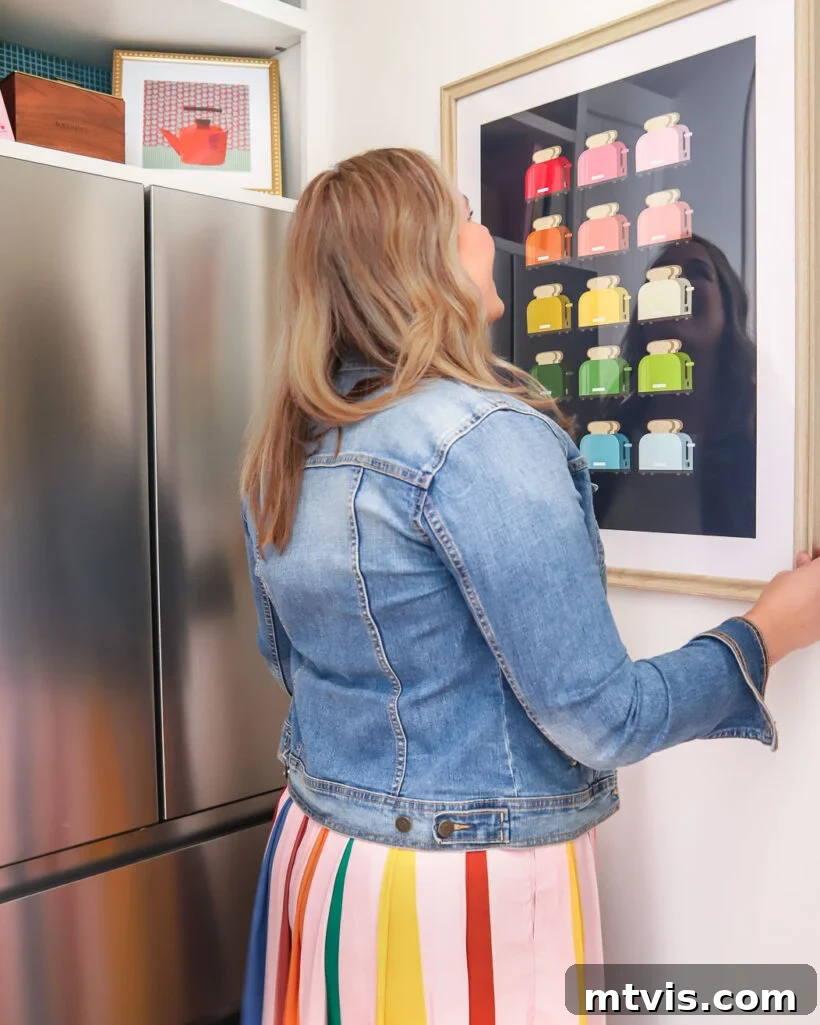 A person hanging colorful artwork in a newly designed butler's pantry, showcasing vibrant decor choices.