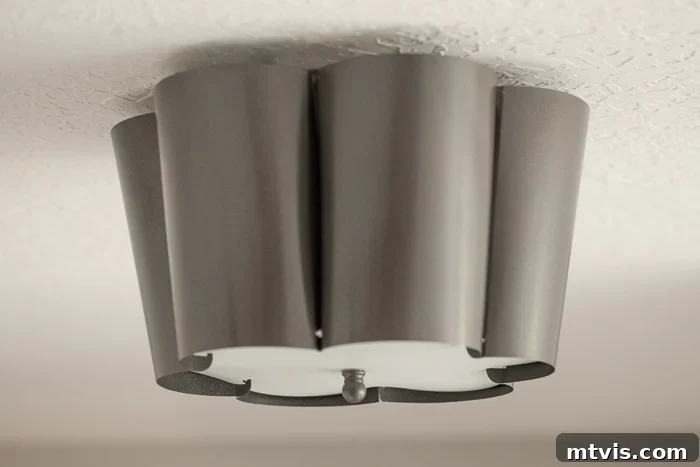 A white flush mount light fixture was spray-painted metallic grey and hung against a white ceiling.