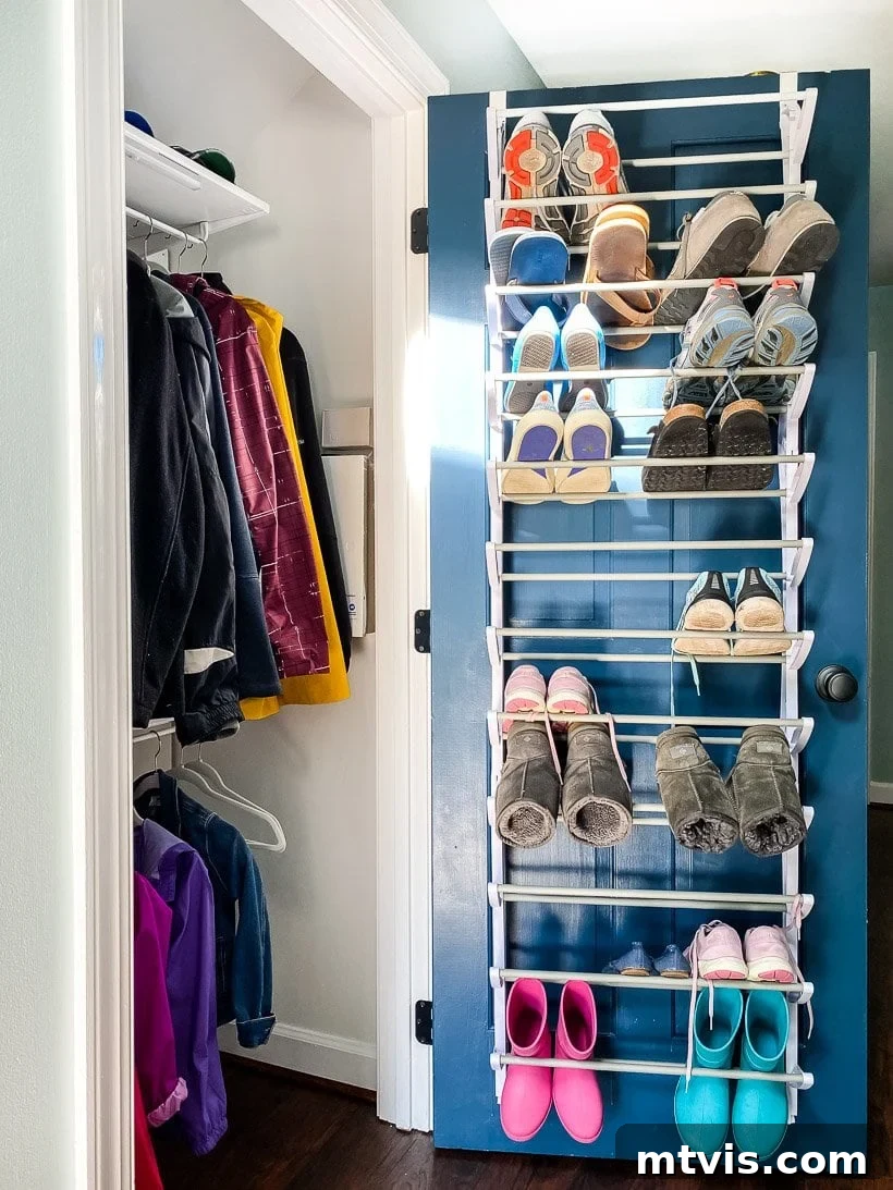 Transform Your Closets: 7 DIY Makeovers and Our Go-To Systems 11 A coat closet has coats hanging both high and low, and the blue door is open showing an over the door shoe rack with multiple shoes on it.