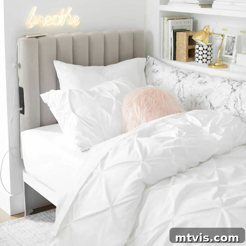 Ultimate Dorm Room Style Ideas and Shopping Sources 7 Pottery Barn showcases clever dorm room ideas to optimize limited space, featuring a quilted headboard with integrated device charging capabilities. The headboard backs an all-white bed with crisp linens, complemented by a tall, full white bookcase, offering both style and essential storage.