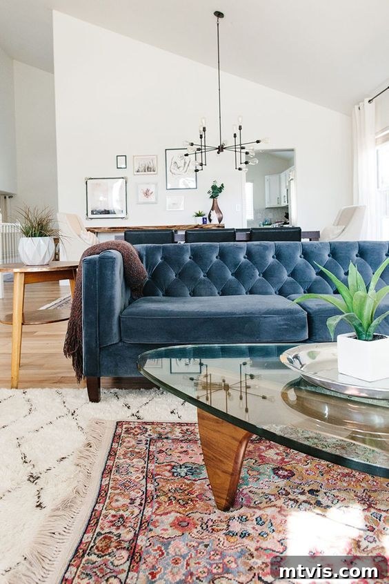 Mastering Living Room Rug Sizes 11 photo showing blue velvet sofa with two legs placed on larger area rug that has a smaller oriental rug layered on top of it