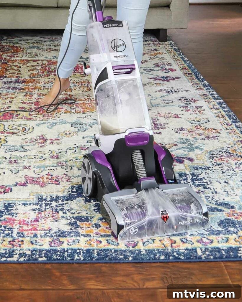 Woman operating a Hoover SmartWash Carpet Cleaner on a large area rug in a living room.