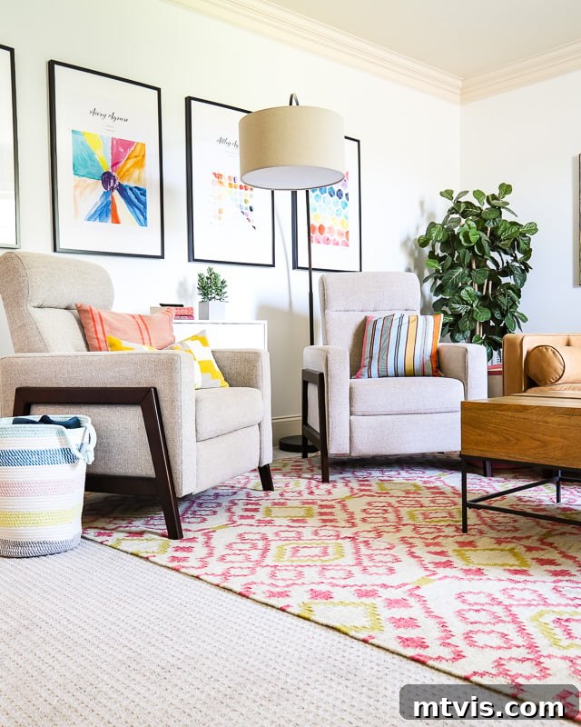 Two accent chairs sit in a colorful family room on a pink graphic print area rug from Annie Selke, creating a cozy seating area.