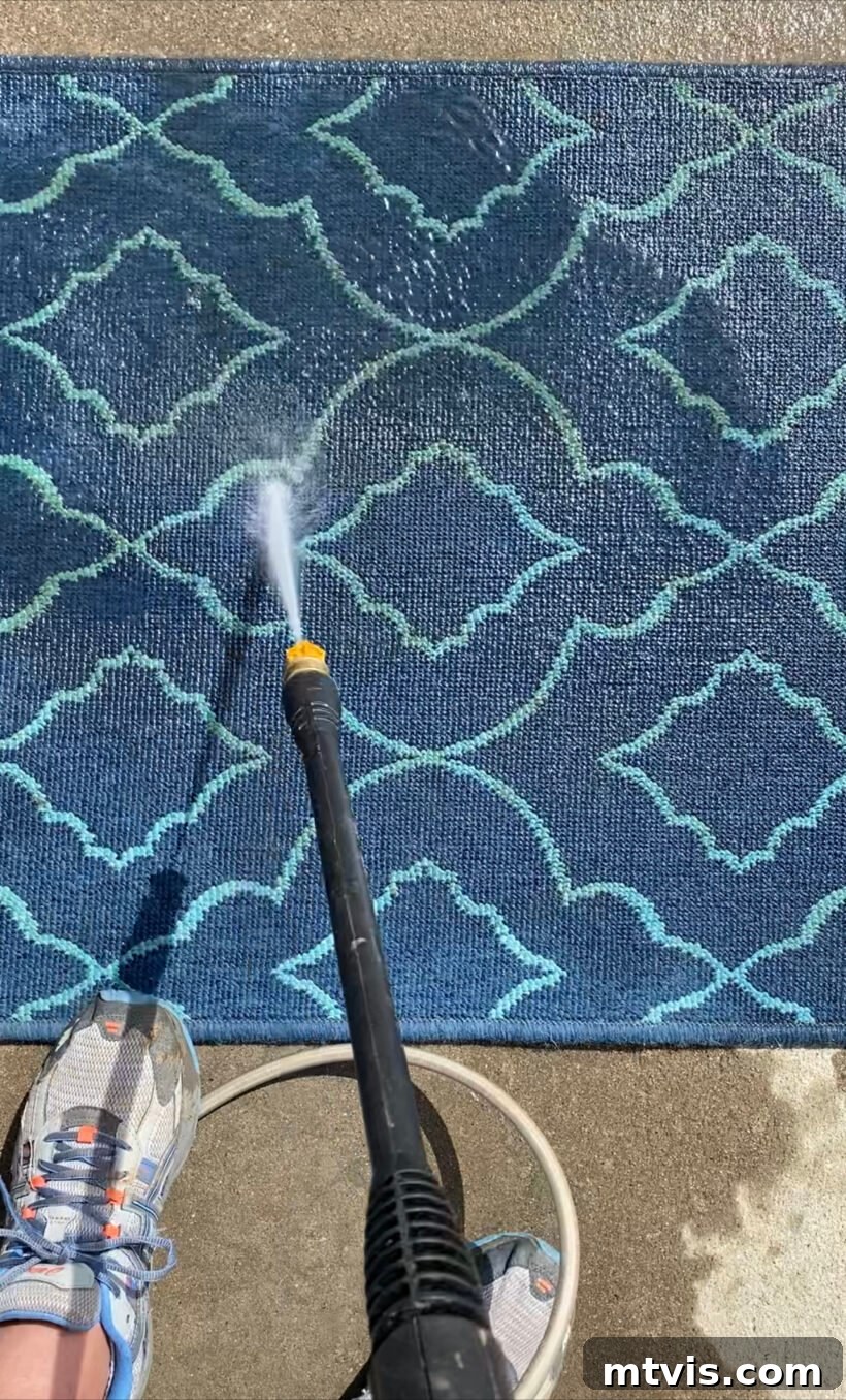 Unlock the Secrets to a Pristine Outdoor Rug 5 Pressure washing an outdoor rug on a driveway