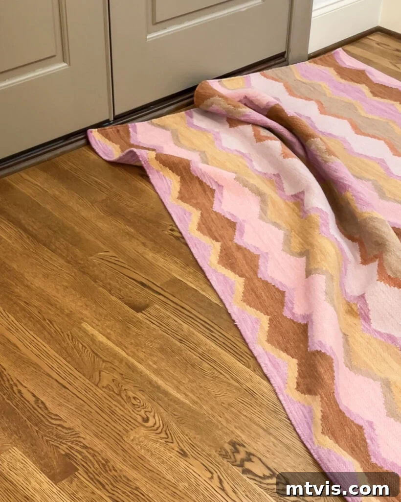 Mastering Flat Rugs Simple Solutions 6 A bunched-up pink patterned rug in front of a doorway, highlighting the need for a rug pad or grippers.