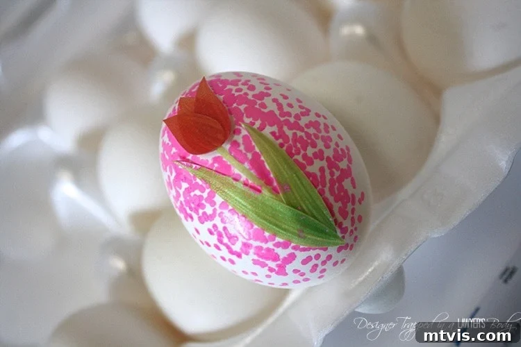 A freshly dotted Easter egg with a craft sticker still in place, resting on a surface and allowing the Sharpie paint to dry before the sticker is peeled off.