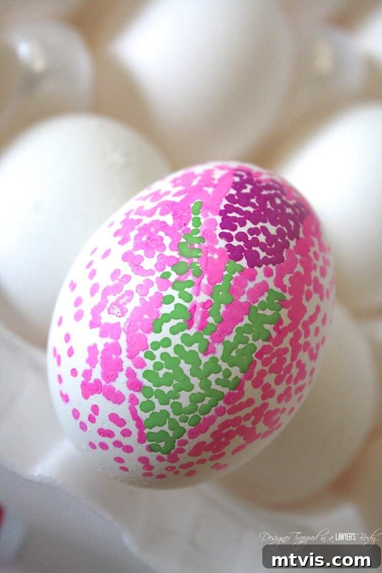 A finished dotted Sharpie Easter egg featuring a vibrant green and blue gradient pattern around a white tulip-shaped negative space, demonstrating the clean reveal of the design.