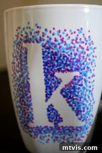 A white ceramic mug decorated with colorful dotted Sharpie designs, showcasing how the easy dotted technique can be applied to create personalized gifts.