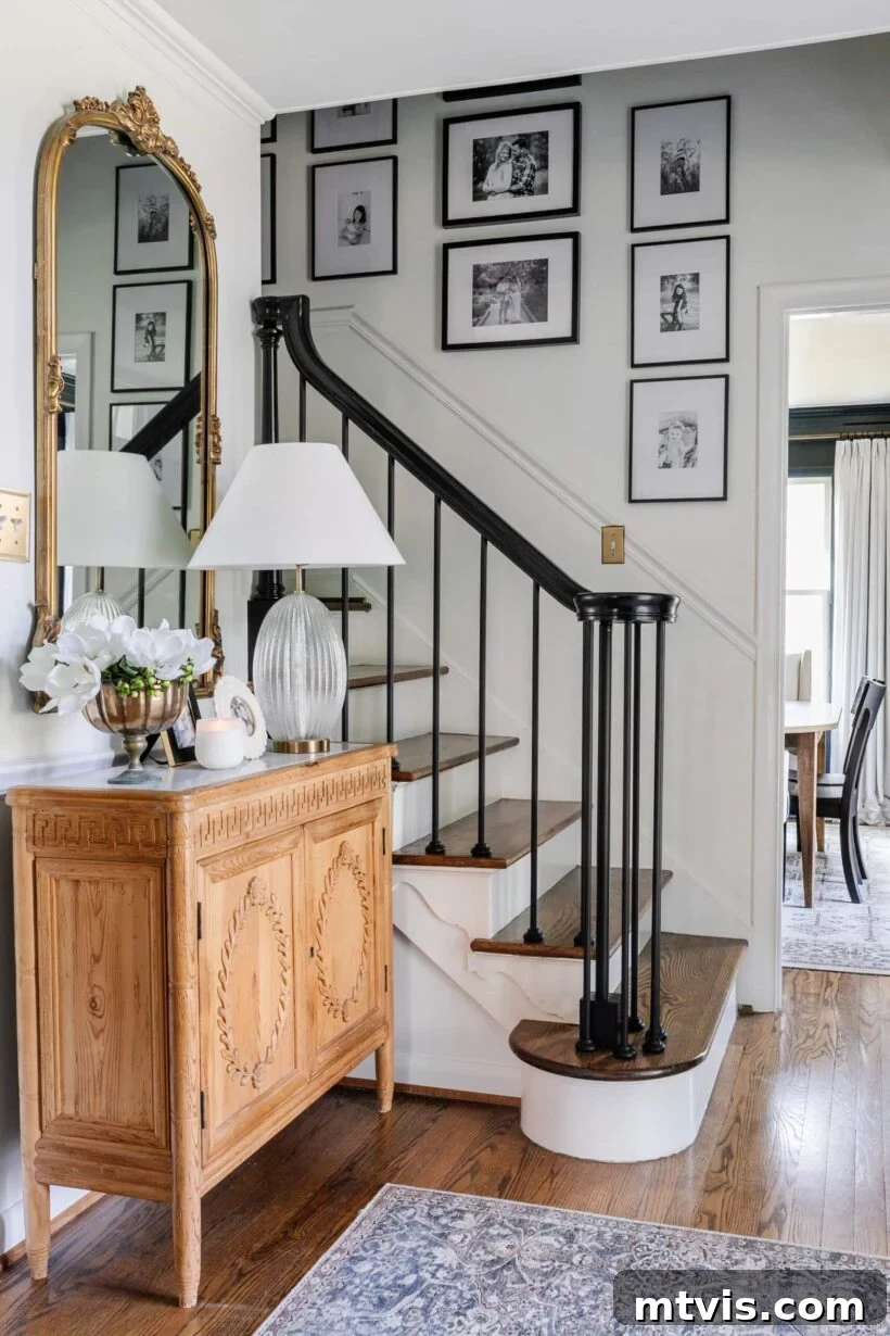 15 Stylish Stair Railing Concepts to Elevate Your Home 5 A black and white staircase has a sleek, modern look with white-matted framed photos leading up the steps.