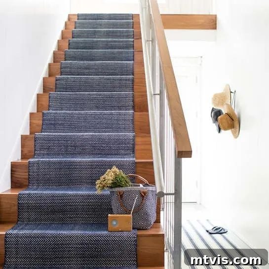 15 Stylish Stair Railing Concepts to Elevate Your Home 8 A wooden staircase with a blue carpet runner shows how to style a metal handrail to feel warm and inviting.