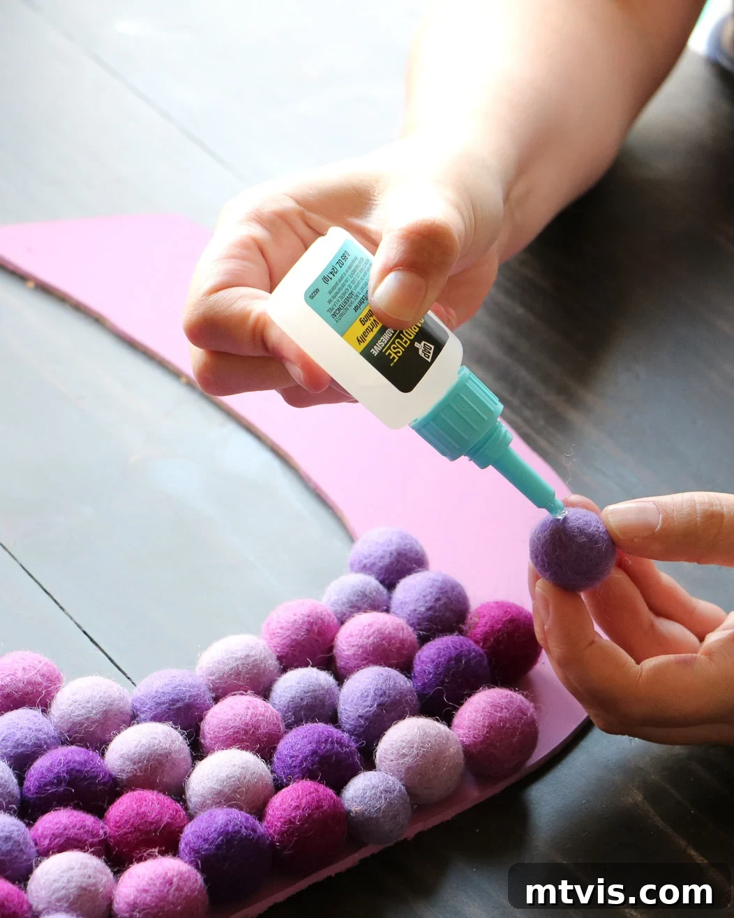 Woman carefully gluing colorful felt balls onto a DIY wall letter with RapidFuse adhesive