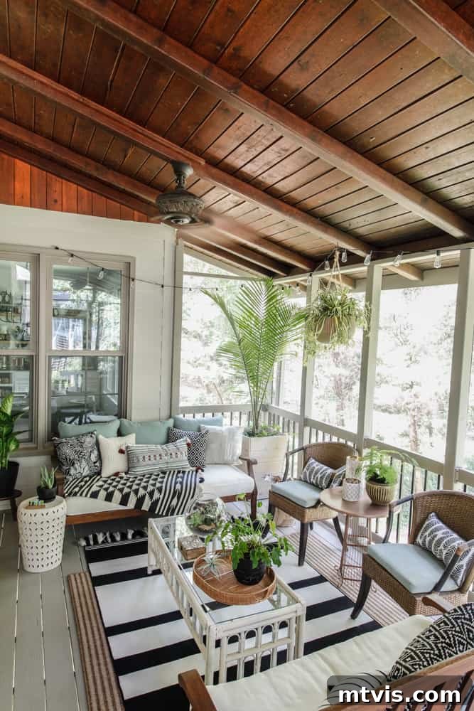 Screened Porch Retreats: Designs for Blissful Outdoor Living 11 A screened-in porch with a stained ceiling, black and white boho decor, a glass and wicker coffee table and lots of pillows, blankets and potted plants.