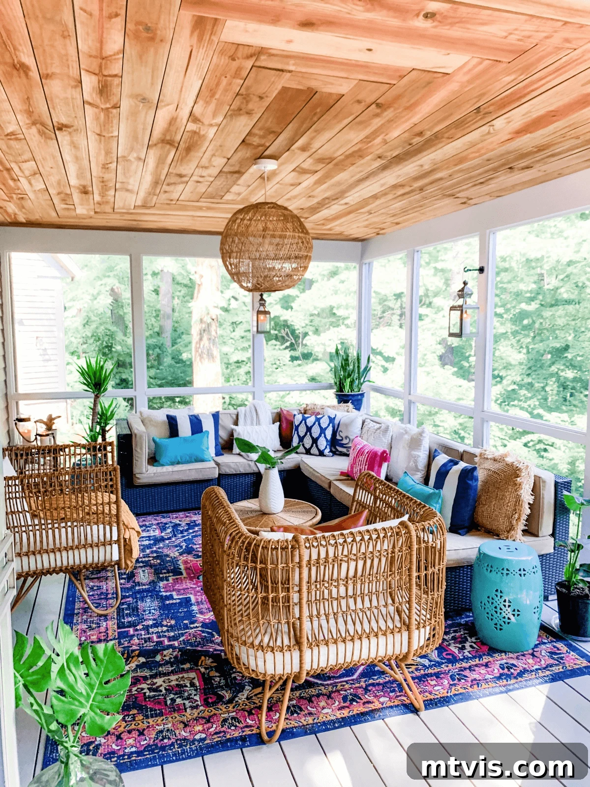 Screened Porch Retreats: Designs for Blissful Outdoor Living 12 This screened-in porch idea has a stained wood ceiling decorated with bright pinks and blues and rattan furniture on a bright area rug.