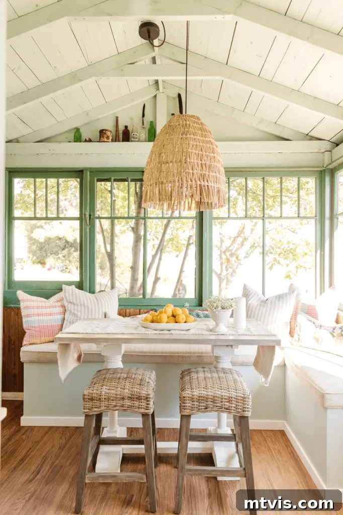 Screened Porch Retreats: Designs for Blissful Outdoor Living 6 This screened-in porch idea includes an eating area with built in bench seats, green windows, a white wooden table with stools and a hanging grass chandelier over the bowl of oranges.